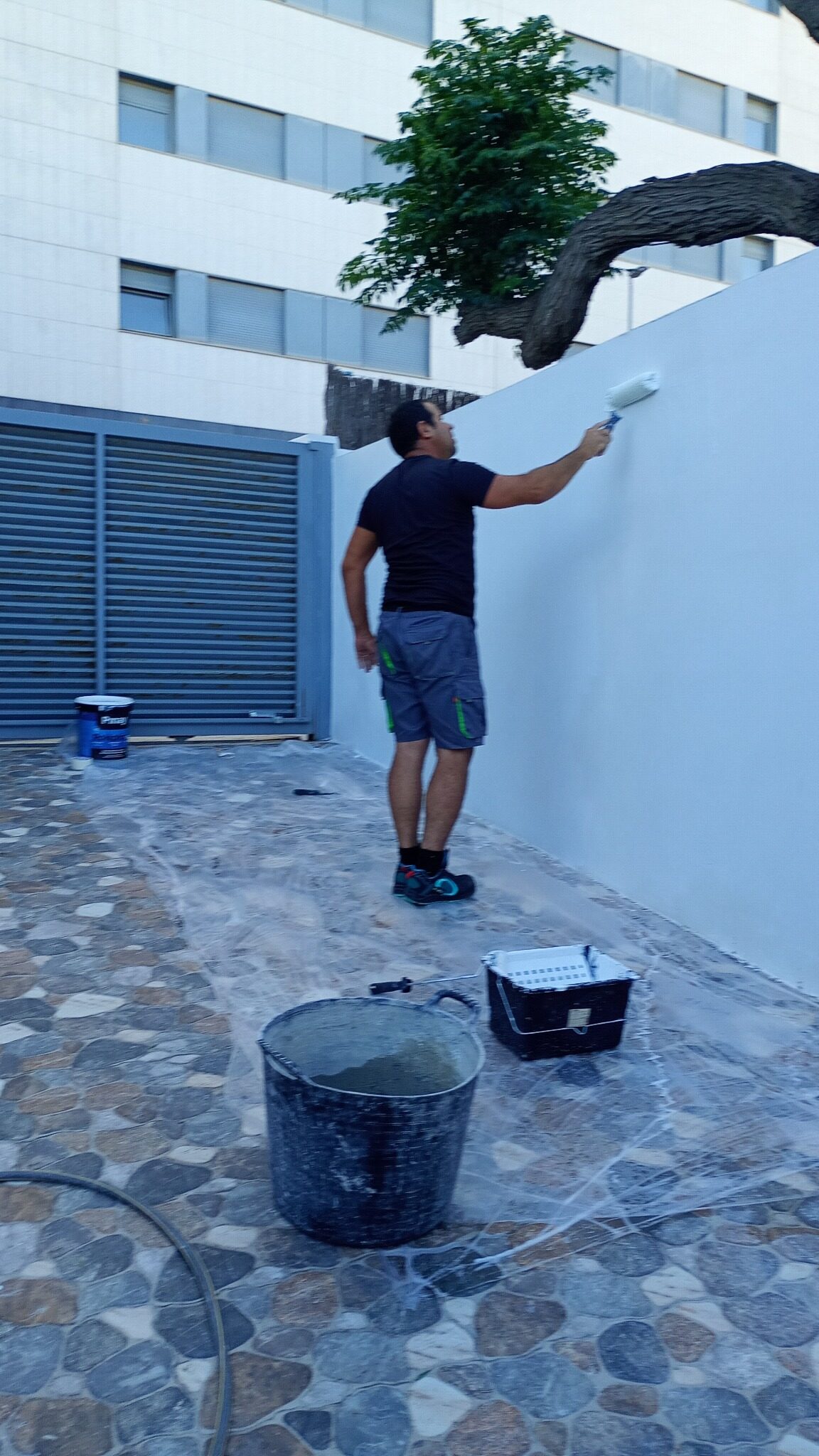 Eddy Ramírez aplicando pintura en una pared exterior
